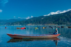 Man in boat on Lake Pokhara below Annapurna